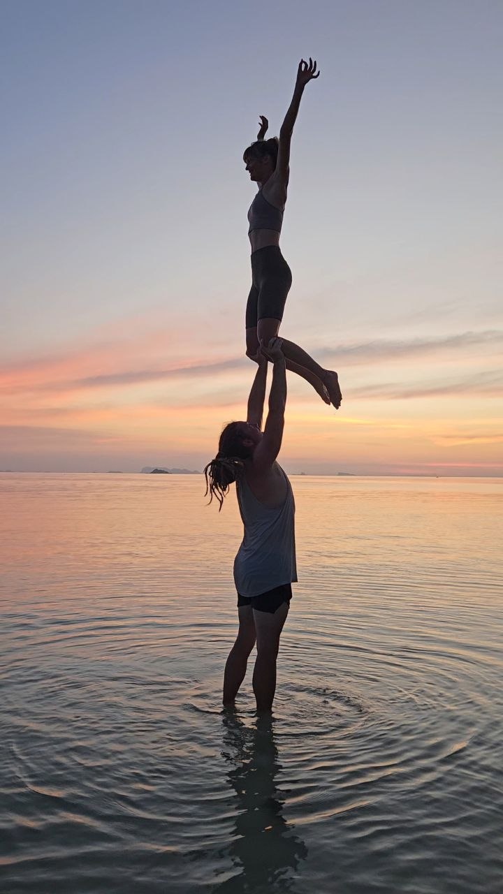 Cedric lifting a partner high above his head at sunset