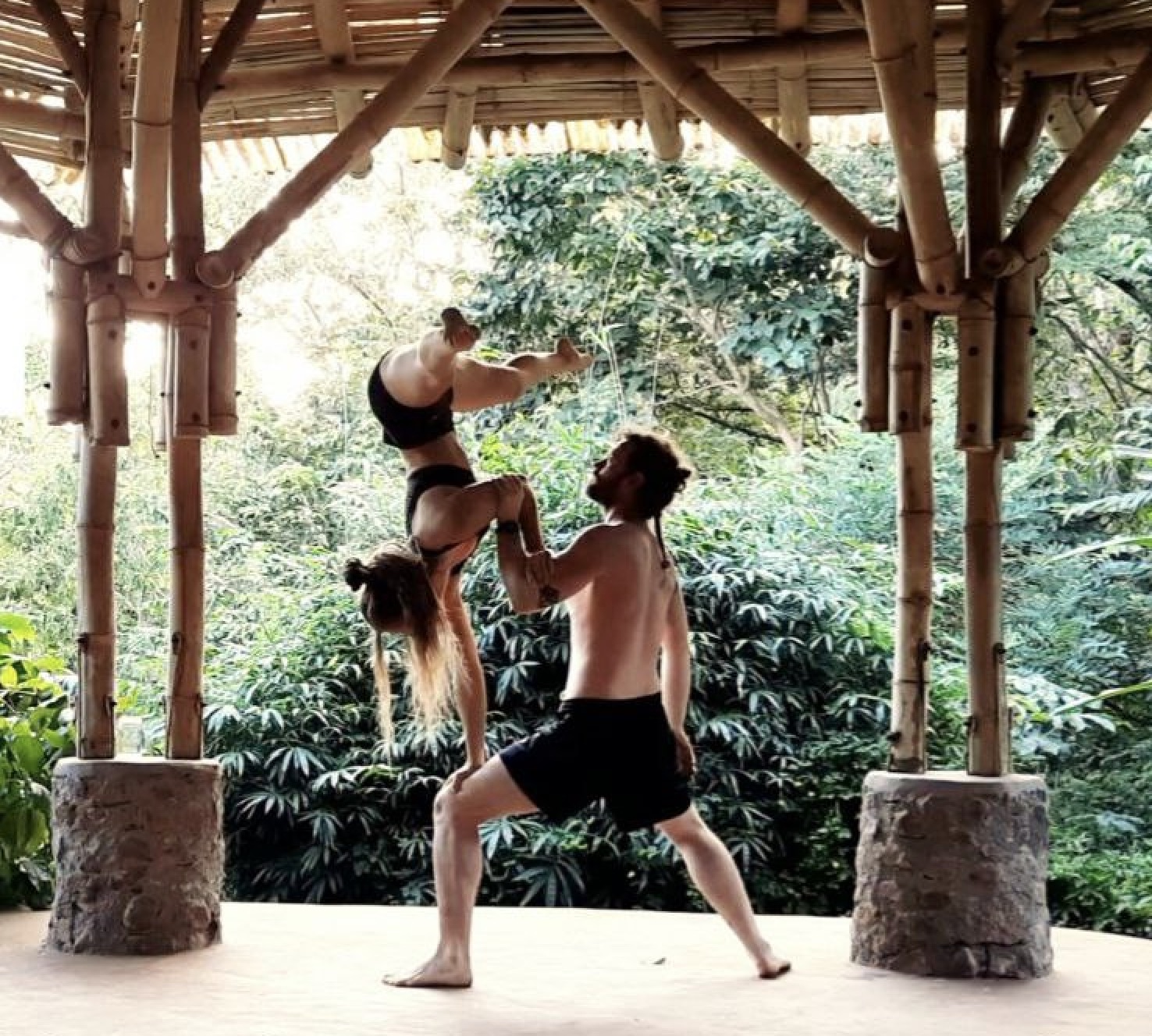 Partner acrobatics under a bamboo pavilion in the jungle