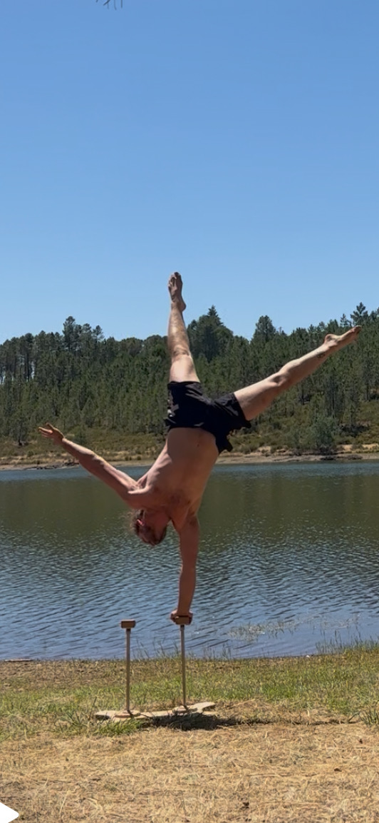 Cedric in a one-arm handstand on canes by a lake